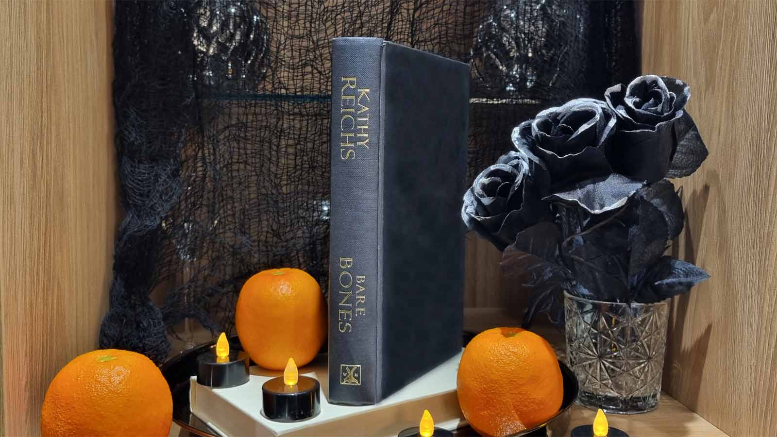 A thriller book amidst festive Halloween black roses and orange props