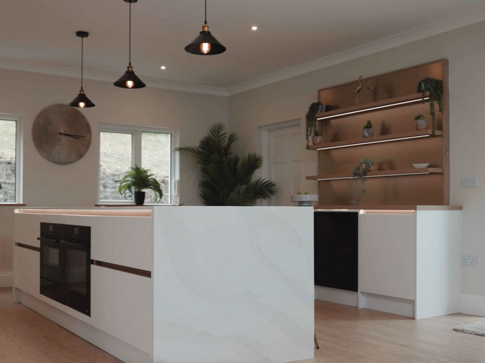 A white kitchen with stone worktops and floating oak shelving