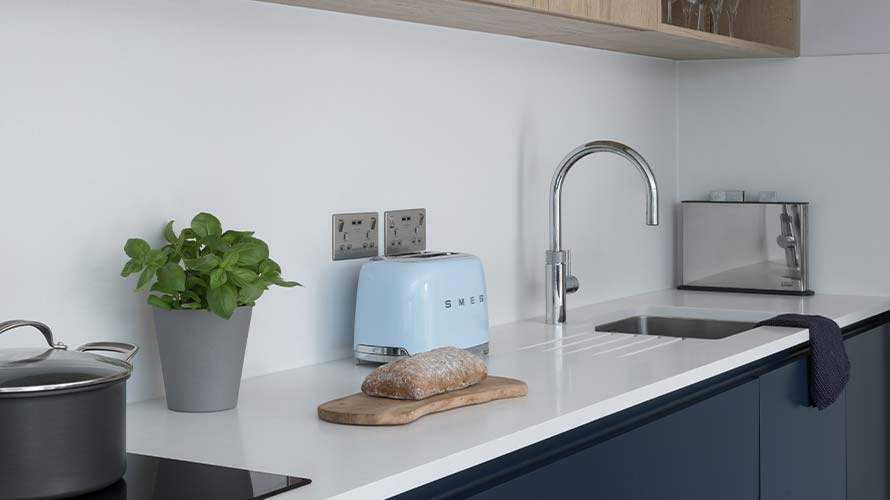 A modern blue handleless kitchen featuring white worktops