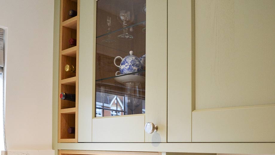 Light green kitchen cabinets with wine shelving