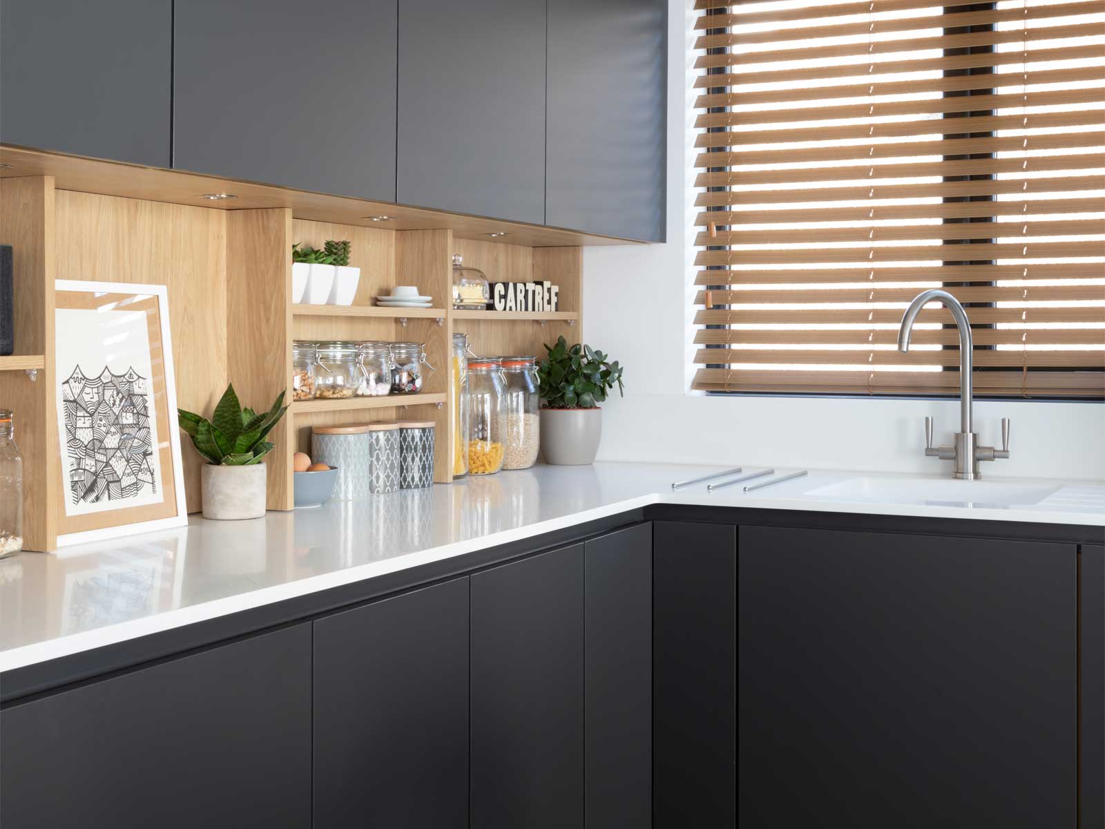 Open kitchen shelving designed in Portland oak amidst black kitchen cabinets