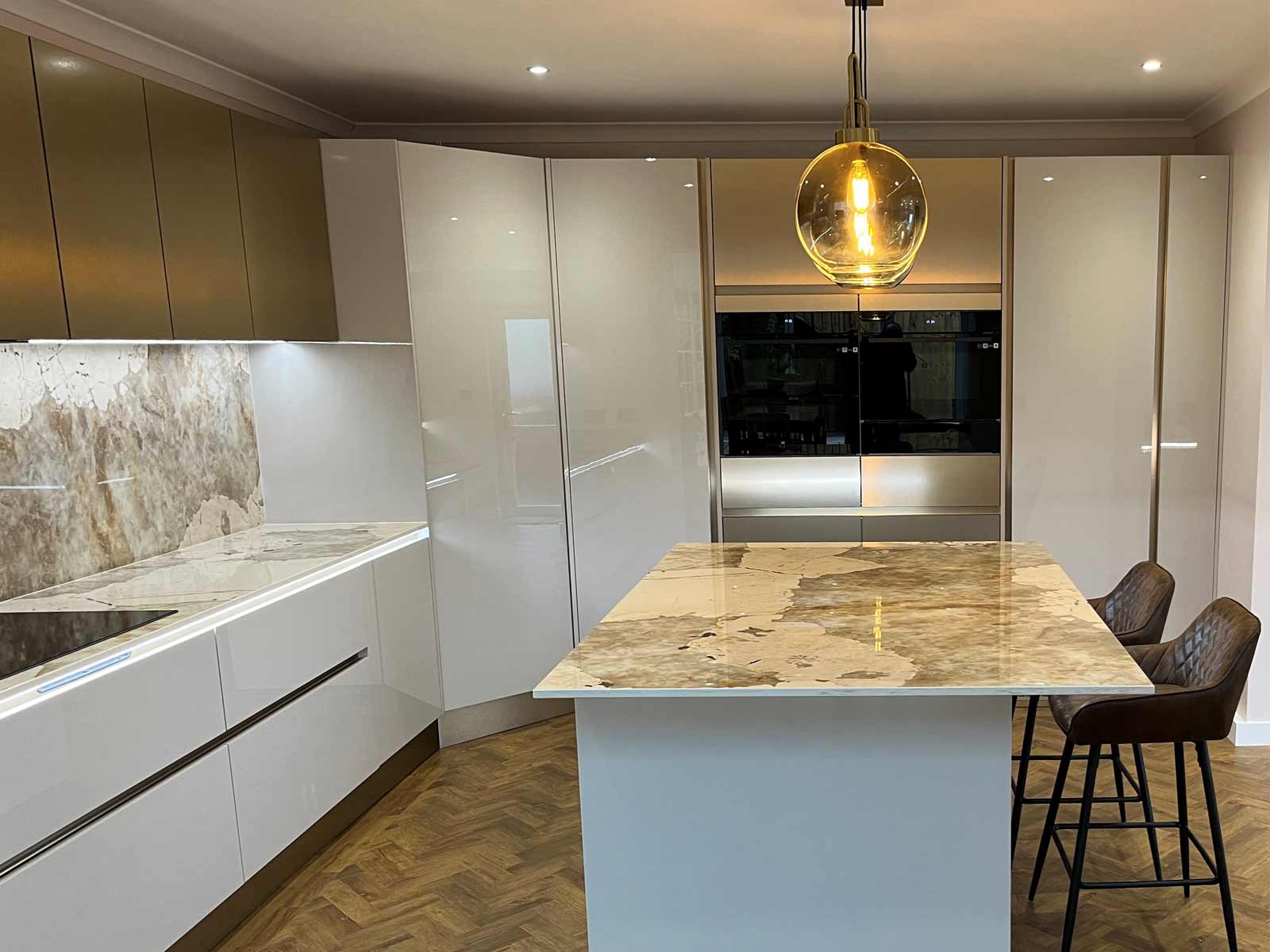 A cashmere-style kitchen with handleless doors and a stone splashback
