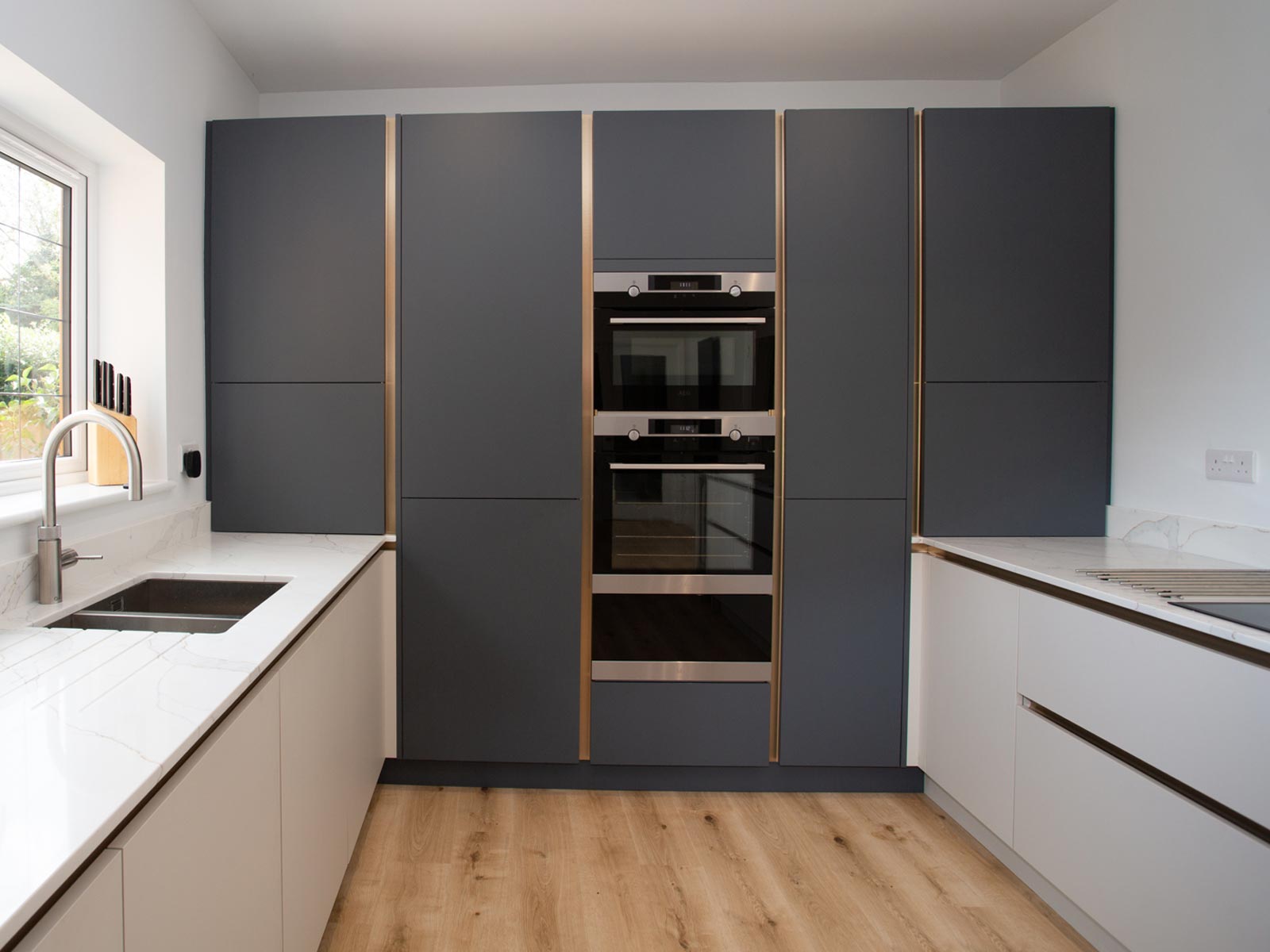 A matt cashmere kitchen with pale grey and onyx cabinet doors
