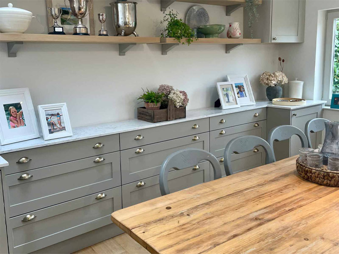 A kitchen design with a wooden kitchen table and grey for kitchen doors