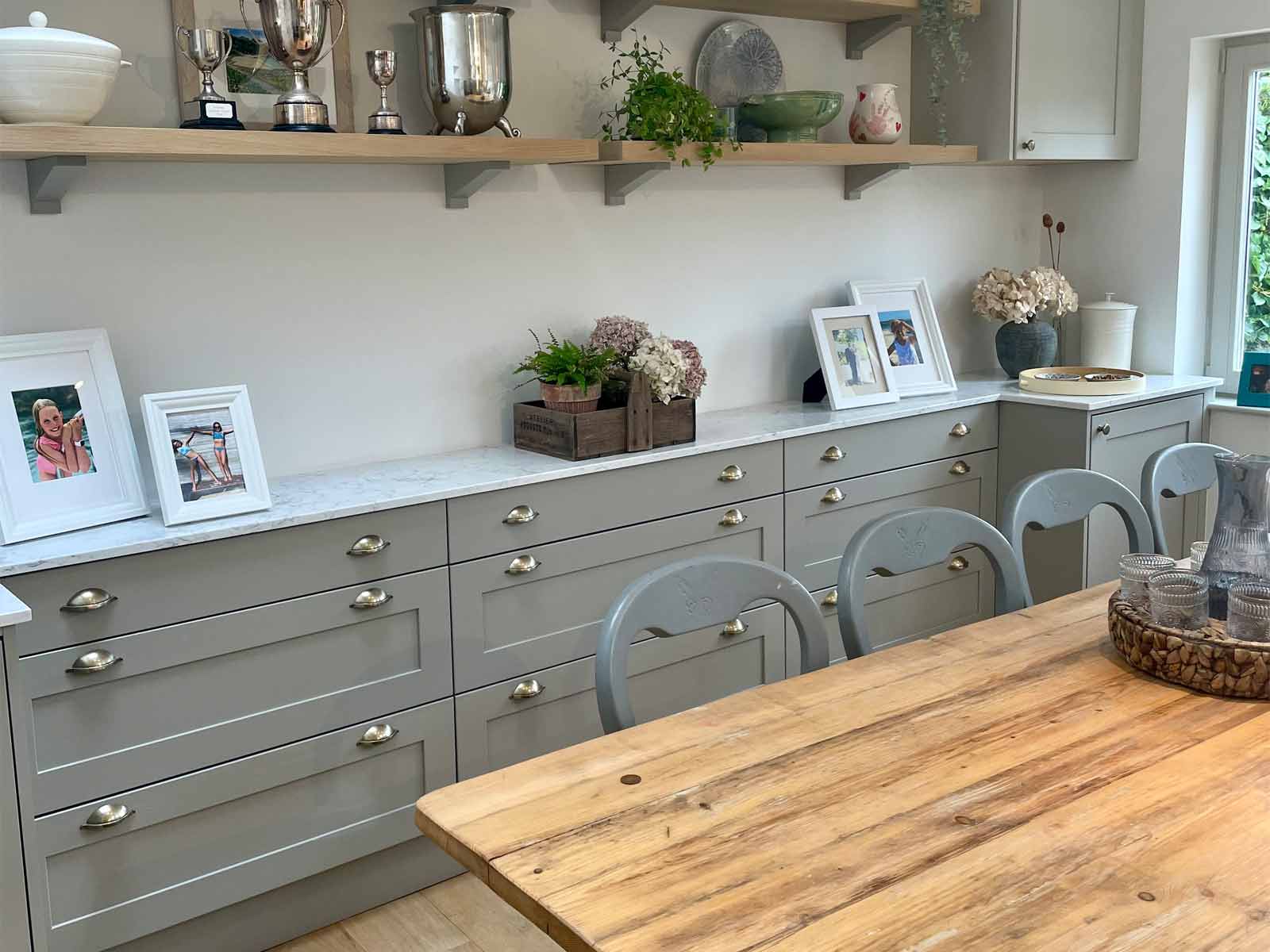 A kitchen design with a wooden kitchen table and grey for kitchen doors