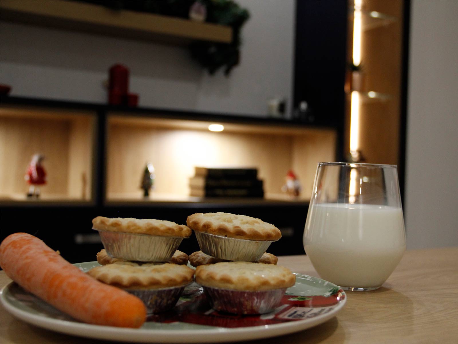 A carrot and mine pies on a plate alongside a glass of milk