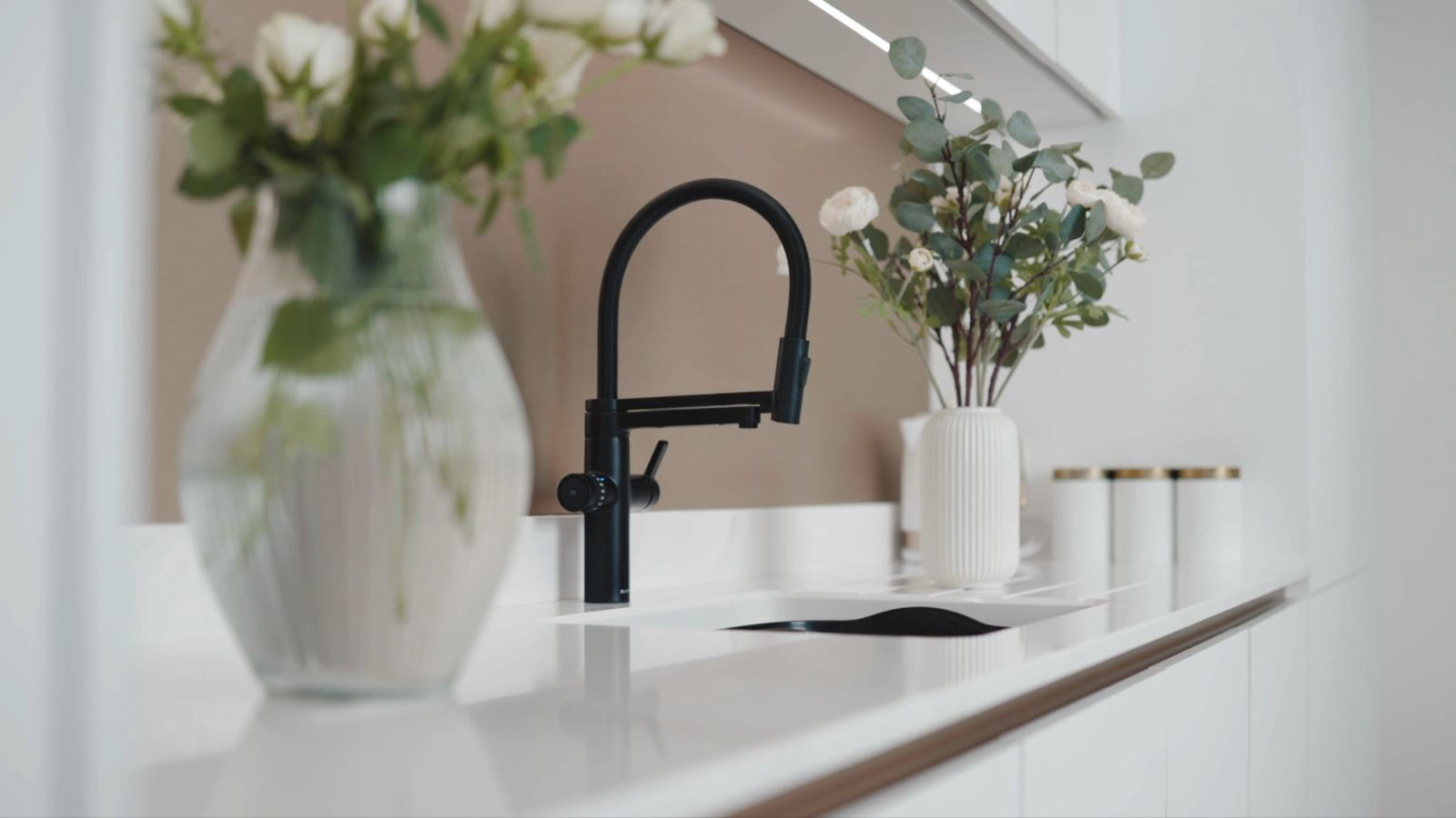 A minimalist white kitchen with a marble worktop