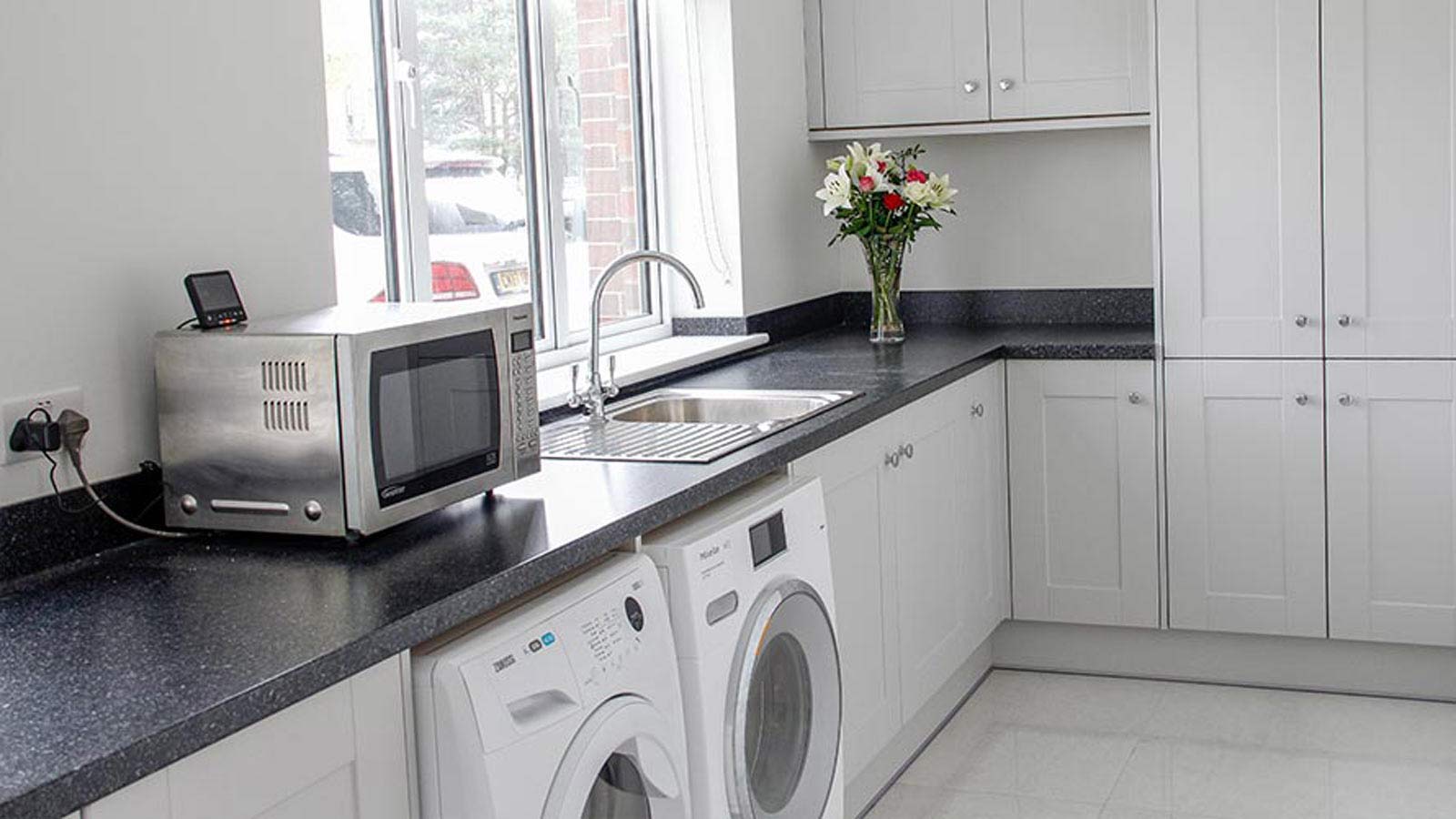 Light grey utility room with washing machine and condenser tumble dryer