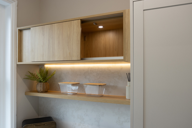 An open sliding door kitchen cabinet in Portland Oak with lights