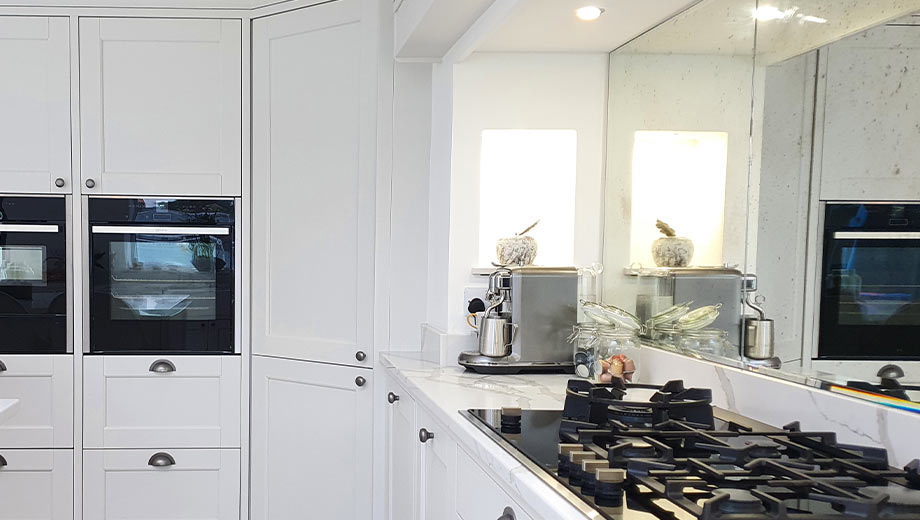 Shaker kitchen with mirrored splashback, a corner pantry and white units
