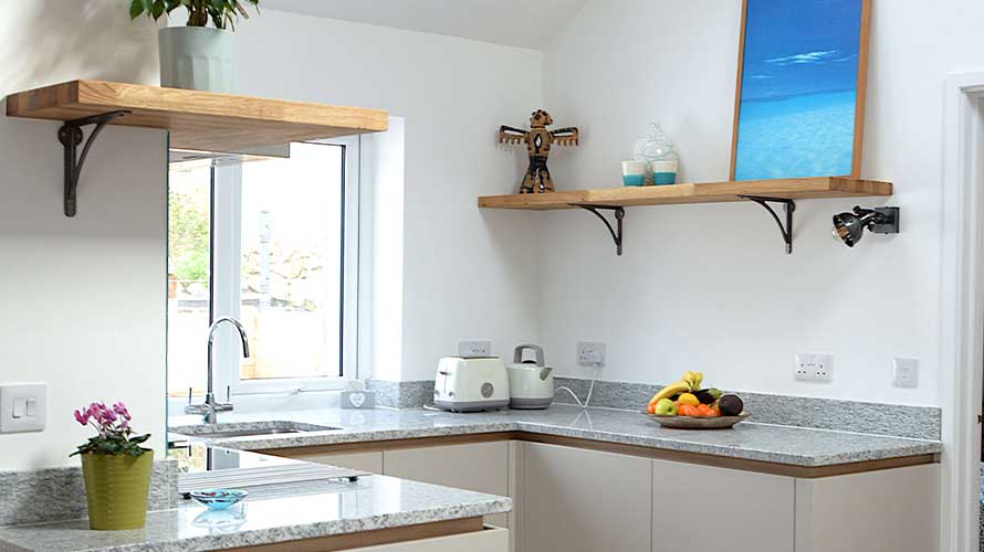 Open shelving in a small kitchen comprising oak shelves and write walls